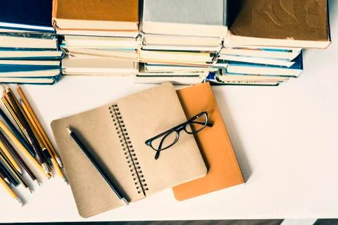 Stack of old books, textbook, notebook, glasses and pencils on white table in Stock Photos