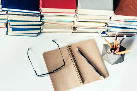 Stack of old books, textbook, notebook, glasses and pencils on white table in Stock Photos