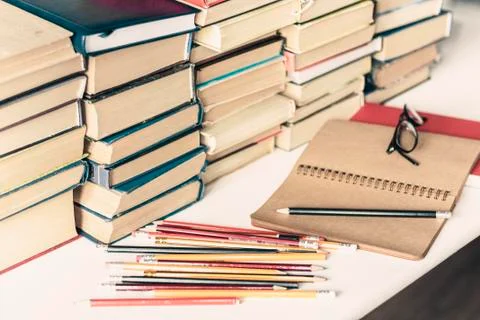 Stack of old books, textbook, notebook, glasses and pencils on white table in Stock Photos