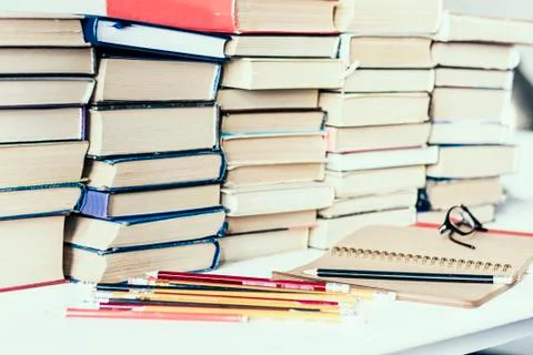 Stack of old books, textbook, notebook, glasses and pencils on white table in Stock Photos