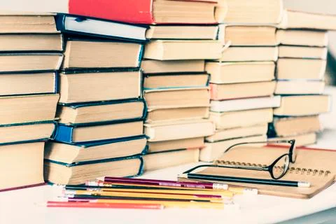 Stack of old books, textbook, notebook, glasses and pencils on white table in Stock Photos