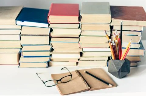 Stack of old books, textbook, notebook, glasses and pencils on white table in Stock Photos