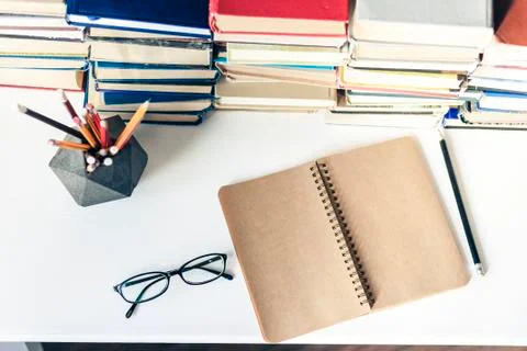 Stack of old books, textbook, notebook, glasses and pencils on white table in Stock Photos