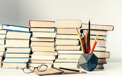 Stack of old books, textbook, notebook, glasses and pencils on white table in Stock Photos