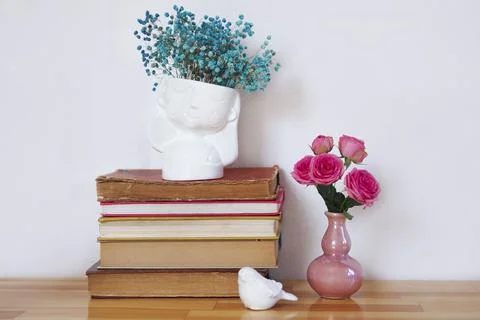 A stack of old books with vases of flowers. Stock Photos