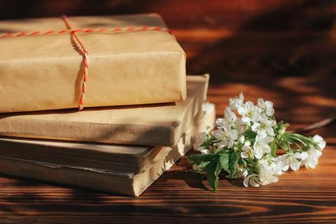 A stack of old books on a wooden background with a sprig of a flowering tree Photos