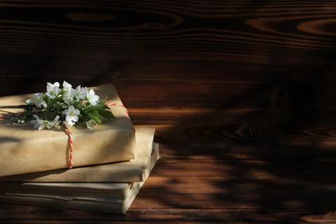 A stack of old books on a wooden background with a sprig of a flowering tree. Photos