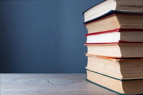 Stack of old books on wooden table and gray background with copyspace to left Stock Photos