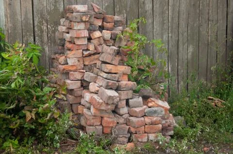 Stack of old bricks on the fence background Stock Photos