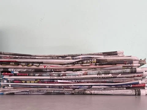 Stack of Old Chinese Newspapers Against Plain Wall Stock Photos
