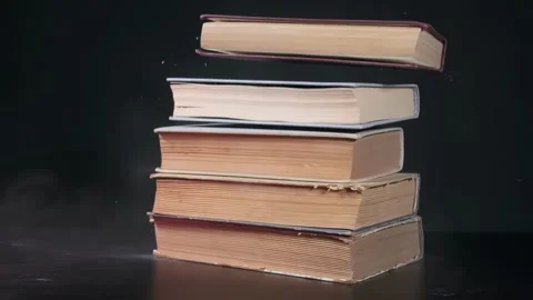 A stack of old dusty books falls on the table, a stack of old books, slow motion Stock Footage 264873764