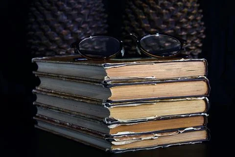 Stack of old dusty books, glasses and book holders Stock Photos