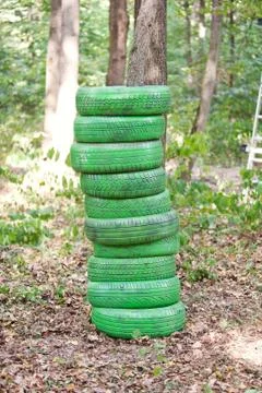 Stack of old green tires in the forest Stock Photos
