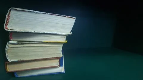 Stack of old hardcover books with worn pages on green shelf Stock Photos