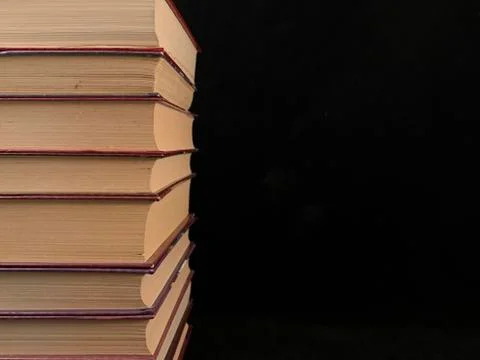 A stack of old hardcover textbooks, on a black background. Thick Books are st Stock Photos