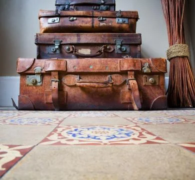 Stack of old leather luggage on tiled floor Stock Photos