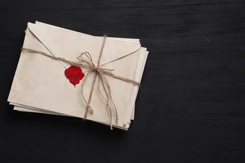 Stack of old letter envelopes tied with twine on black wooden table, top vi.. 写真素材