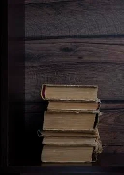 Stack of old paper books on dark shelf, vertical image Foto stock