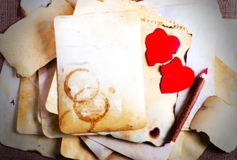Stack old papers, notebook, wooden pencil and two vintage red hearts on burlap Stock Photos