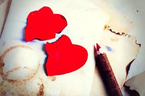 Stack old papers, notebook, wooden pencil and two vintage red hearts on burlap Stock Photos