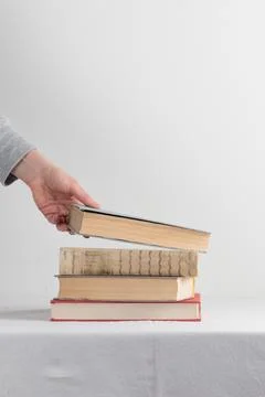 Stack of old rustic vintage books with the hand Stock-Fotos