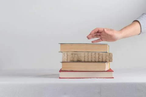 Stack of old rustic vintage books with the hand Stock-Fotos