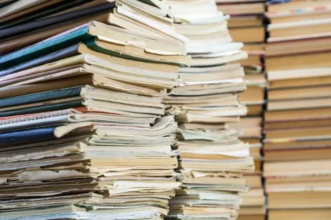 A stack of old school notebooks and a stack of textbooks or books. Stock Photos