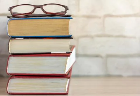 A stack of old thick books and glasses on the table. Stock Photos