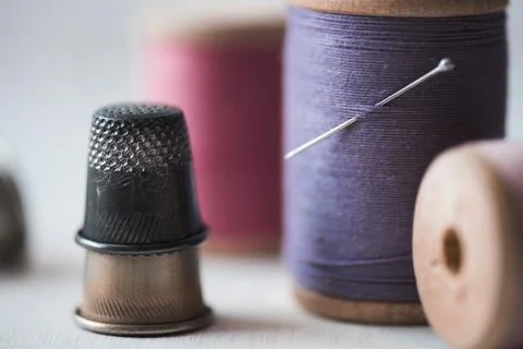 Stack of old thimbles with spool of threads closeup staying on table. Handmad Stock Photos