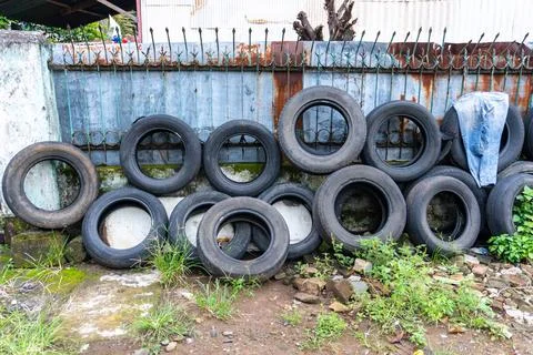 Stack of Old Tires Against Rusty Fence Outdoors Stock Photos