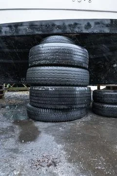 Stack of old tires supporting a boat on land Stock Photos