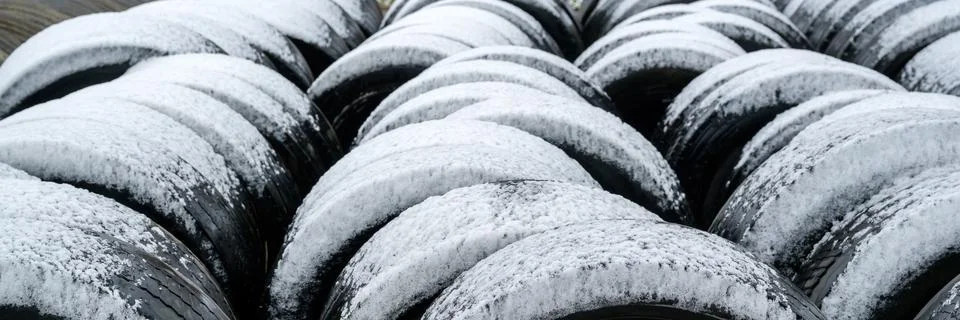 Stack of old used bus vehicle tires covered in winter snow Stock Photos