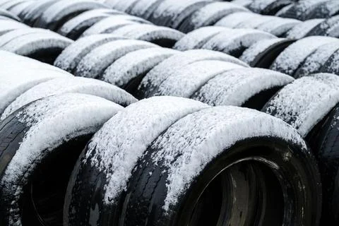 Stack of old used bus vehicle tires covered in winter snow Stock Photos