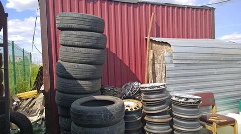Stack of old used car tires and stamped wheel disc. Pile of rubbish. Stock Photos