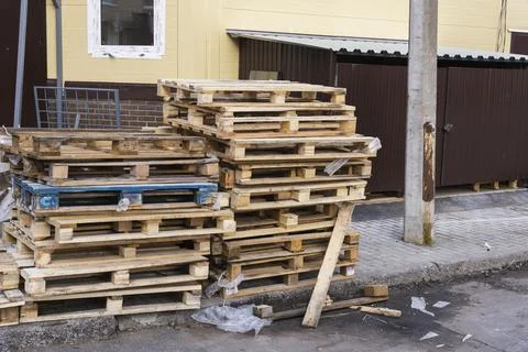 A stack of old wooden pallets in the yard , used pallets stacked on the sidew Stock Photos
