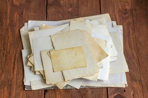 A stack of old yellowed photographs on an old wooden table. Stock Photos