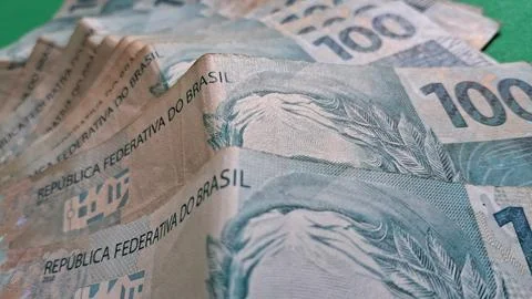 Stack of one hundred Brazilian real banknotes on green surface Stock Photos