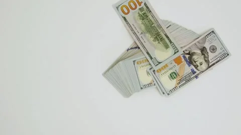A stack of one hundred dollar bills falls onto a white surface. 4K footage Stock Footage 325976884