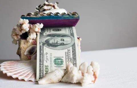 Stack of one hundred dollar bills in a box of seashells Stock Photos