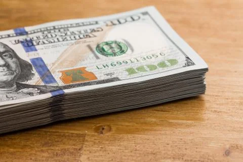 Stack of one hundred dollar bills on a wooden table Stock Photos