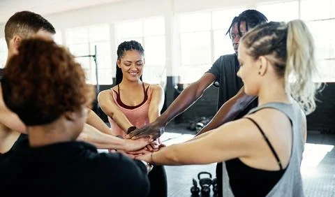 Stack one by one. a cheerful young group of people forming a huddle together Stock Photos