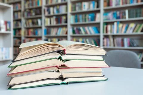 A stack of open books on the table in the library room. Library with bookcases Stock Photos