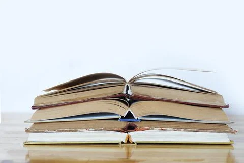 A stack of open books on a wooden table on a white background Stock Photos