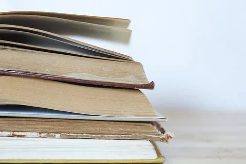A stack of open books on a wooden table on a white background Stock Photos