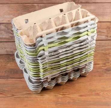 Stack of open empty pulp egg cartons on rustic table Stock Photos