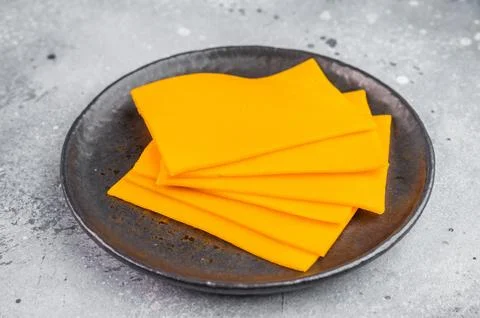 Stack of orange cheese slices on round plate minimal food composition with .. Foto stock
