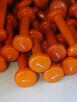 A stack of orange dumbbells with the numbers 0-5 kg on the top Stock Photos