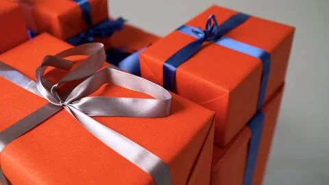Stack of orange gift boxes wrapped with silver and blue ribbons. Stock Photos