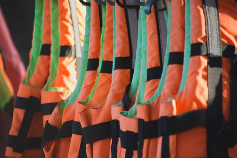 A stack of orange life jackets hanging on a hanger Stock Photos