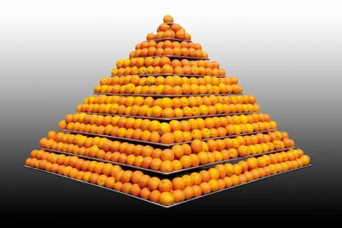 Stack of oranges in pyramid shape against grey background Stock Photos